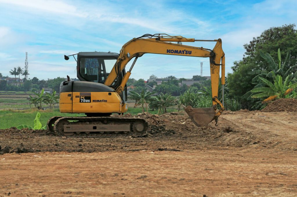 services-01 Yellow excavator on a rural construction site on a sunny day.