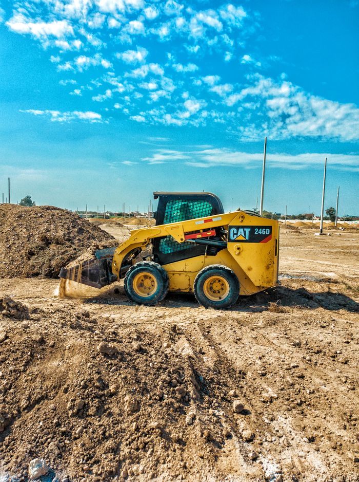 services-02 Skid steer loader at a daytime construction site with blue sky backdrop.